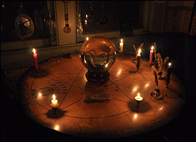 Candle-lit crystal ball on Ouija table